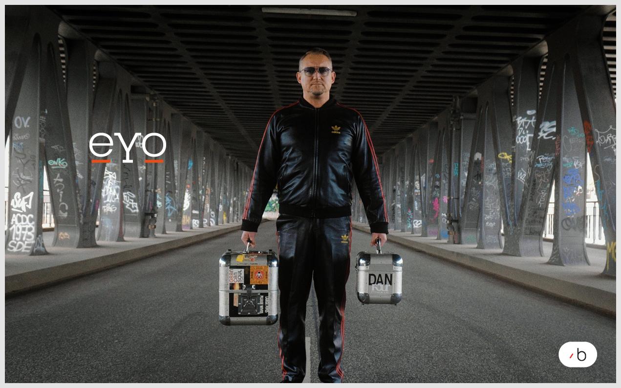 eYo-Ambassador Dan Dombrowe steht mit zwei Musikkoffern auf einer Brücke.